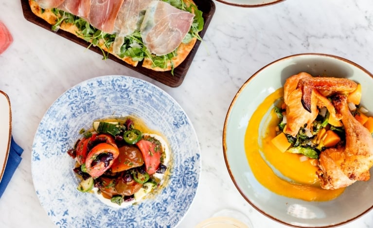 A table set with several plates of food, displaying a diverse selection of appetizing dishes for a communal dining experience.