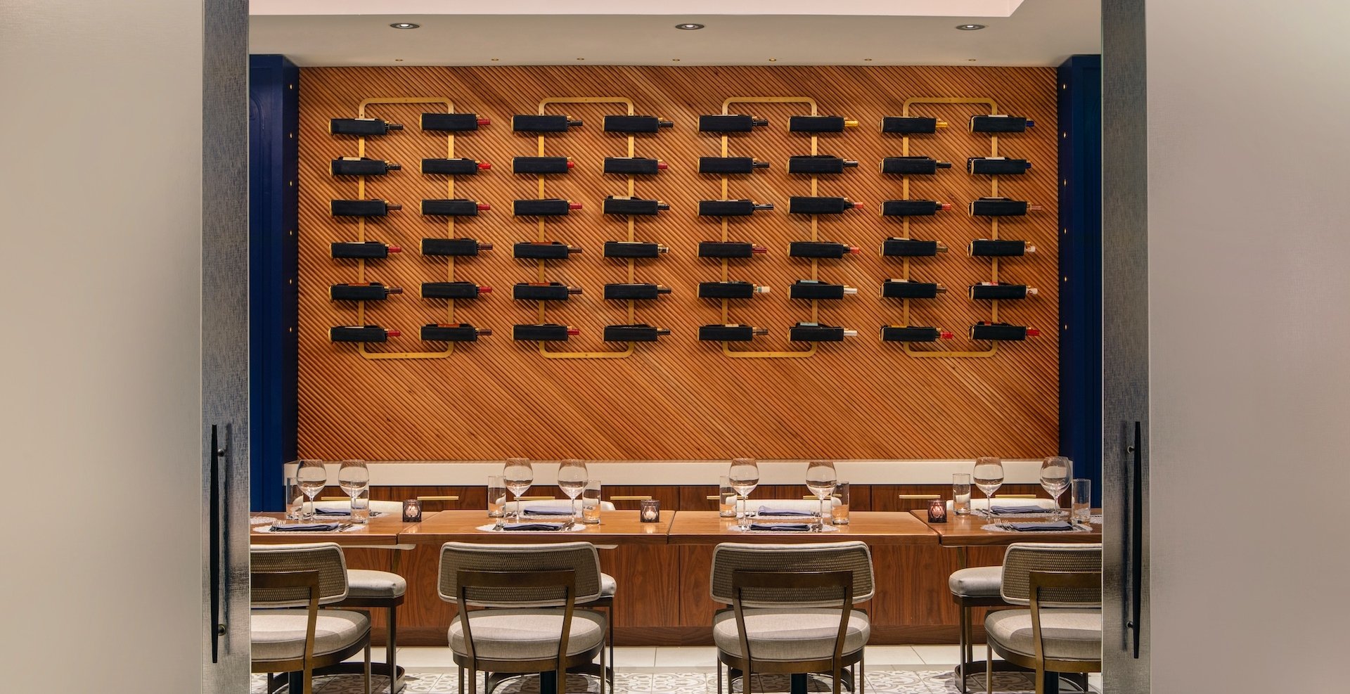 a private dining area with various bottles of wine on the wall