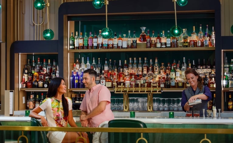 a couple sitting at the lobby bar while a bartender pours drinks
