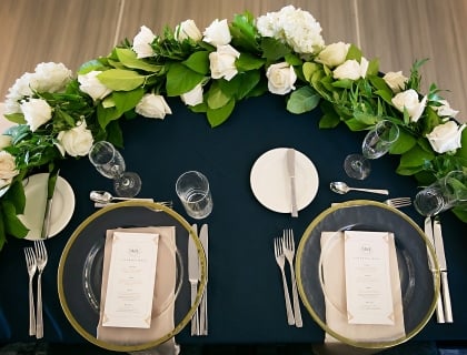 place setting with white roses and a blue table cloth