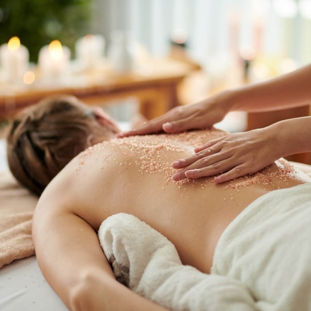 Woman getting exfoliating scrub massage in spa salon
