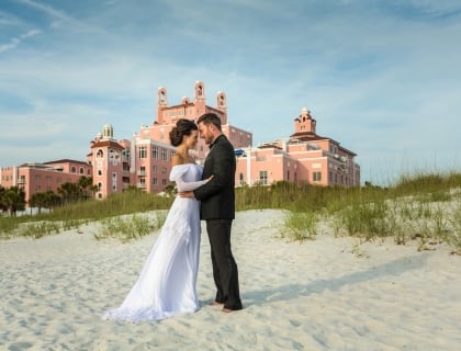 a bride and groom cuddling on the beach