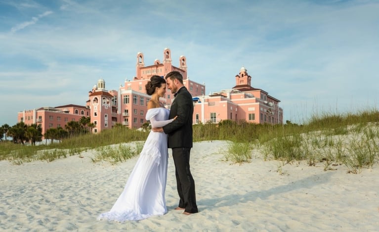 a bride and groom cuddling on the beach