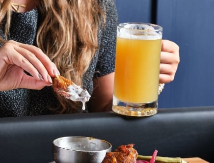 Woman holding a beer and chicken wings