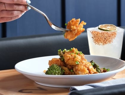 Fried shrimp on a fork with a drink in the background