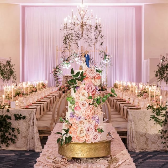 large ballroom decorated with white lace and greenery for a wedding, large wedding cake with bride and groom cake topper